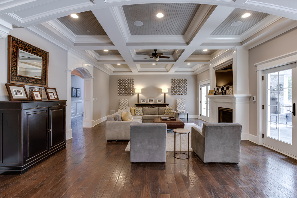 This is an example of a large transitional open concept family room in DC Metro with beige walls, medium hardwood floors, a standard fireplace, a wood fireplace surround and a wall-mounted tv.