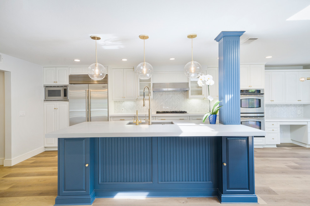 Inspiration for a mid-sized transitional laminate floor and brown floor eat-in kitchen remodel in Orange County with an undermount sink, shaker cabinets, blue cabinets, quartz countertops, white backsplash, mosaic tile backsplash, stainless steel appliances, an island and white countertops