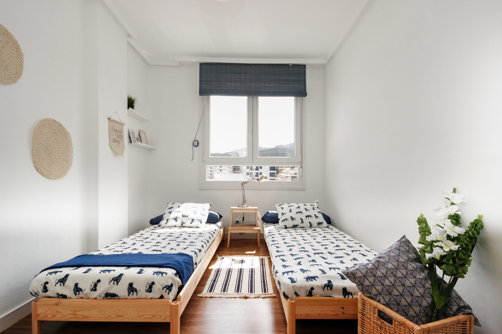 Beach style gender-neutral kids' bedroom in Bilbao with white walls and medium hardwood floors for kids 4-10 years old.