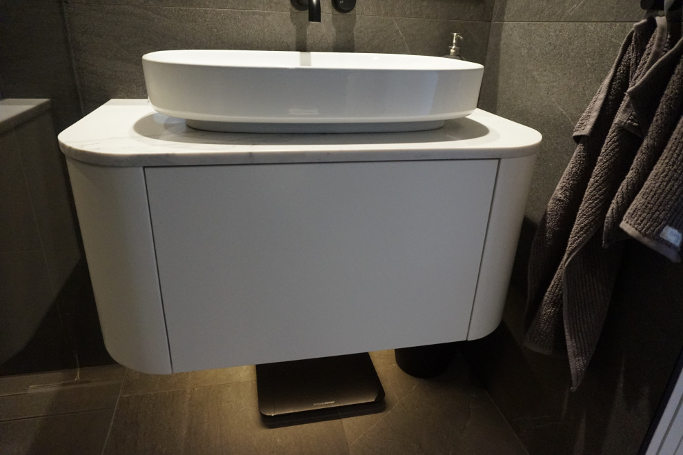 Mid-sized modern bathroom in Sydney with flat-panel cabinets, white cabinets, an open shower, a wall-mount toilet, gray tile, ceramic tile, grey walls, ceramic floors, a console sink, engineered quartz benchtops, grey floor, an open shower, white benchtops, a single vanity and a floating vanity.