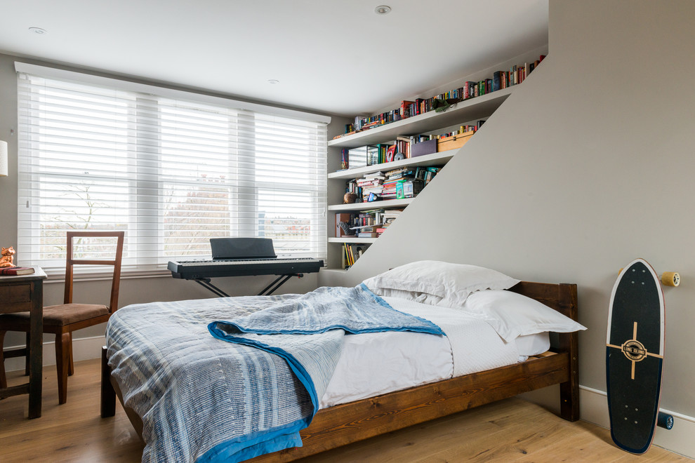 This is an example of a mid-sized eclectic guest bedroom in London with grey walls and light hardwood floors.