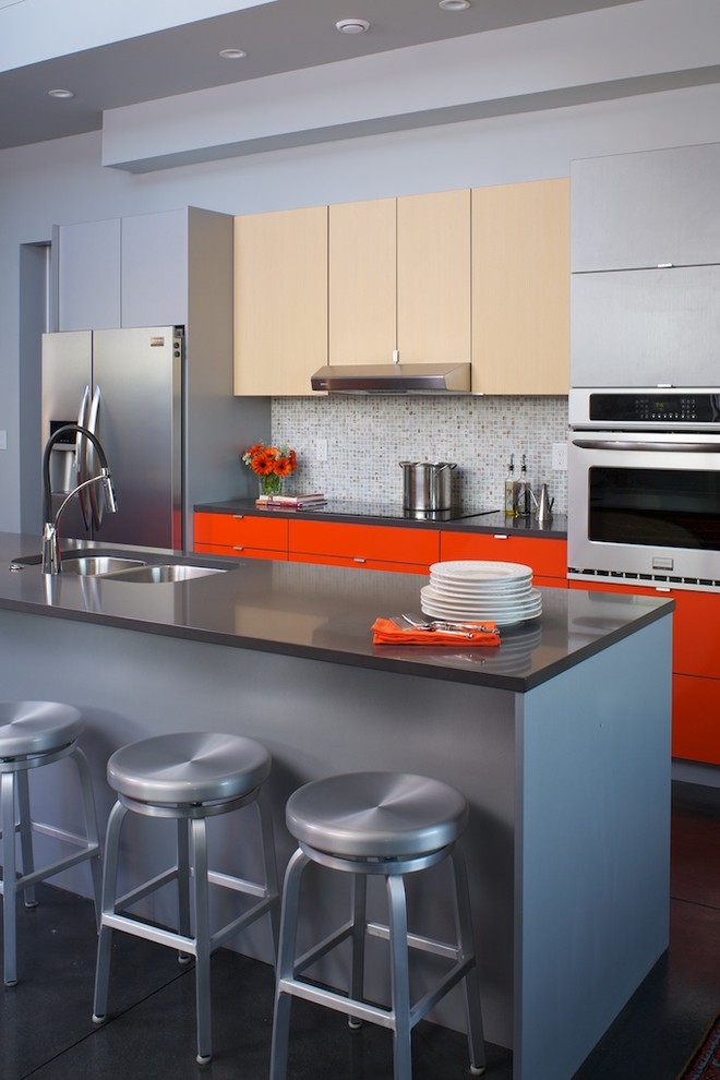 This is an example of a contemporary galley kitchen in Denver with flat-panel cabinets, grey splashback, mosaic tile splashback, stainless steel appliances, with island, a double-bowl sink and orange cabinets.
