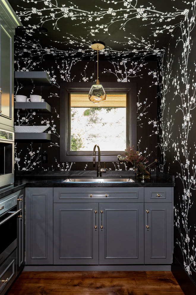 Inredning av ett modernt mellanstort svart svart kök, med en undermonterad diskho, släta luckor, grå skåp, marmorbänkskiva, svart stänkskydd, stänkskydd i marmor, rostfria vitvaror, mellanmörkt trägolv, flera köksöar och brunt golv