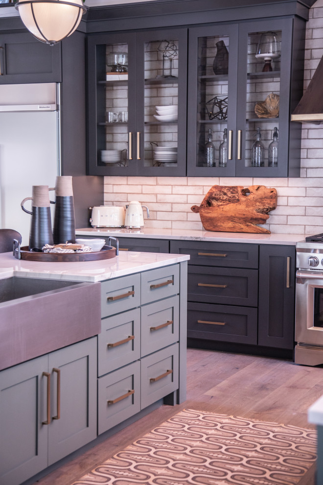 Example of a large transitional u-shaped medium tone wood floor and brown floor open concept kitchen design with a farmhouse sink, shaker cabinets, black cabinets, quartzite countertops, white backsplash, porcelain backsplash, stainless steel appliances, two islands and white countertops