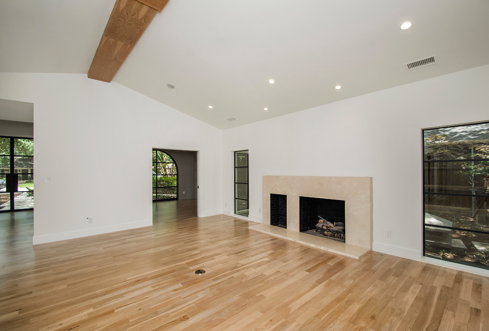 Photo of a large modern formal open concept living room in Dallas with white walls, light hardwood floors, a standard fireplace, a stone fireplace surround and no tv.
