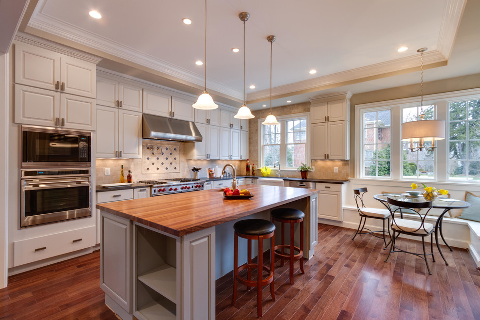 Design ideas for a traditional kitchen in DC Metro with wood benchtops, a farmhouse sink, raised-panel cabinets, beige splashback and stainless steel appliances.