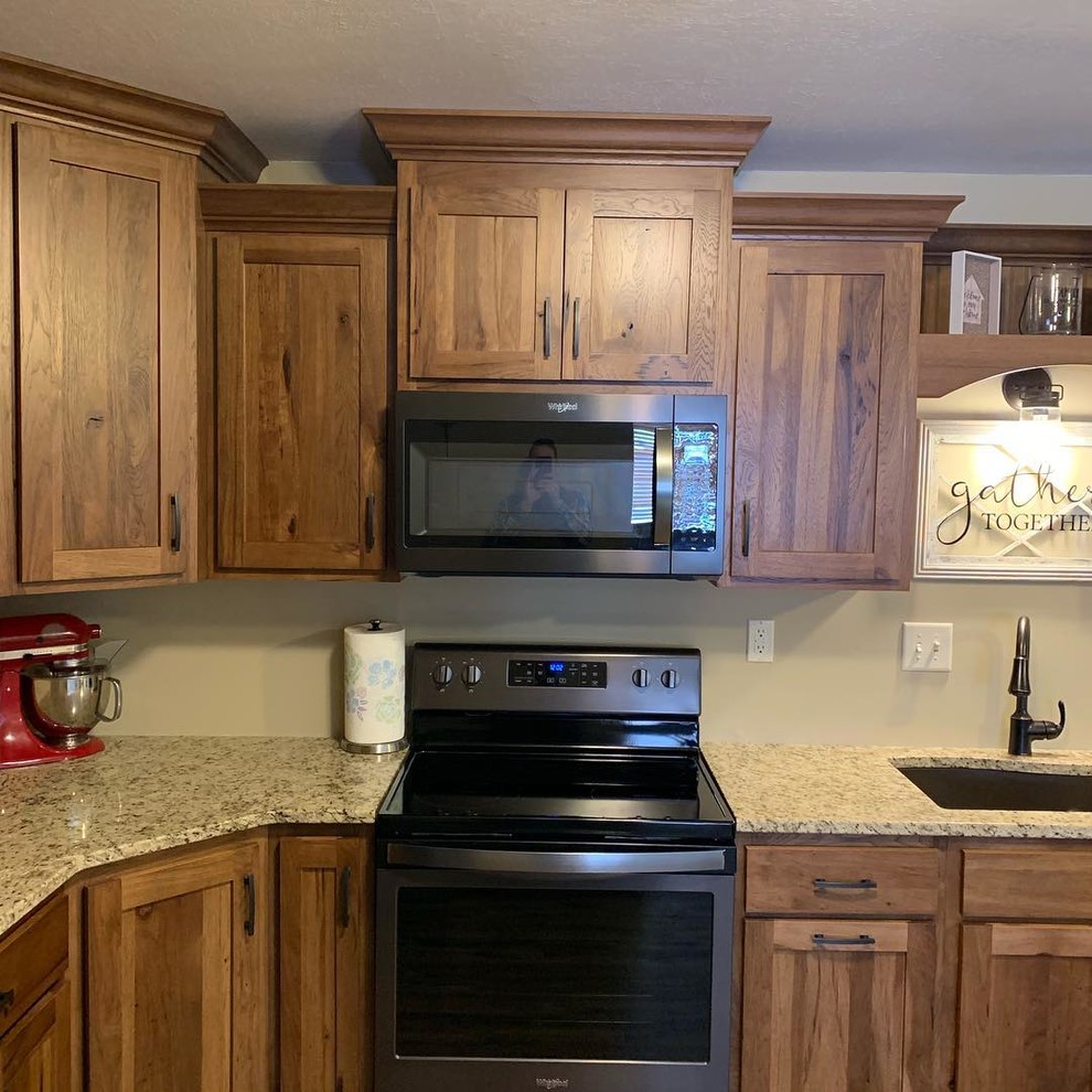 Mid-sized country u-shaped separate kitchen in Omaha with an undermount sink, shaker cabinets, brown cabinets, granite benchtops, black appliances, vinyl floors, multi-coloured floor and multi-coloured benchtop.