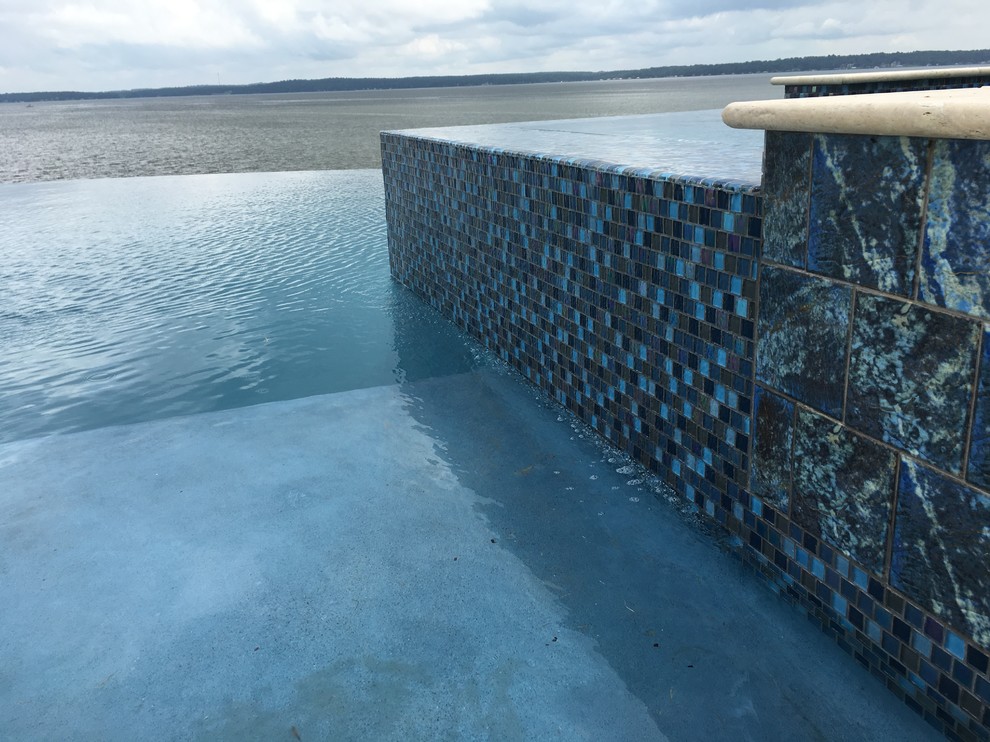 Example of a mid-sized transitional backyard concrete and custom-shaped infinity hot tub design in Austin