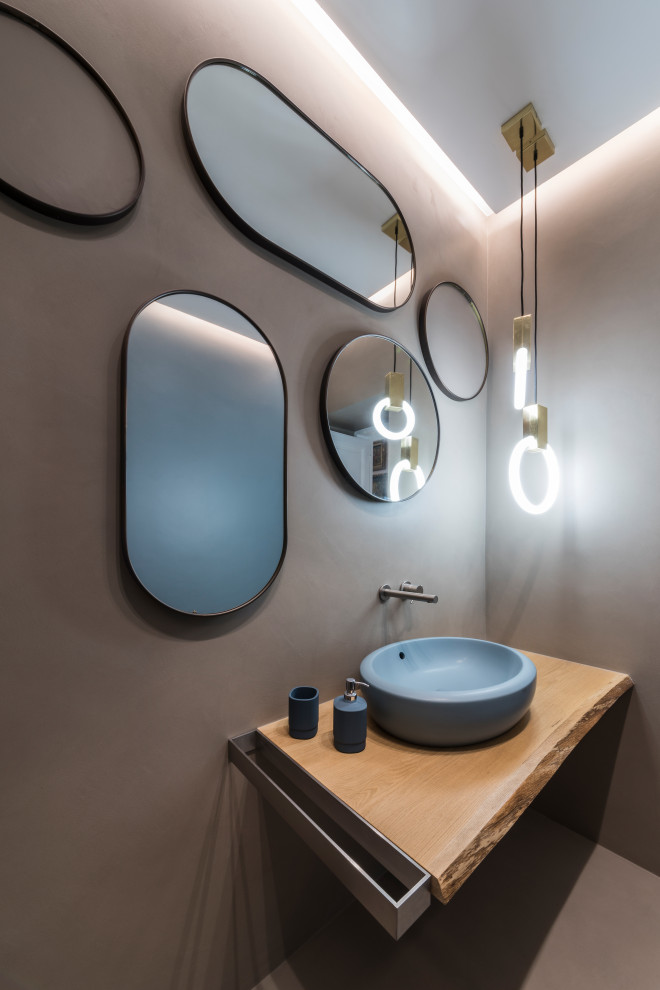 Mid-sized contemporary powder room in Bari with light wood cabinets, a two-piece toilet, multi-coloured walls, wood benchtops, multi-coloured floor and a freestanding vanity.
