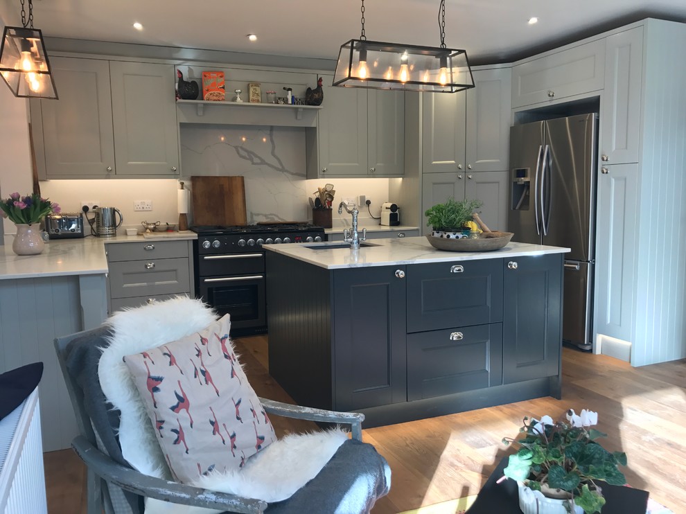 Design ideas for a mid-sized contemporary u-shaped kitchen in Surrey with an undermount sink, recessed-panel cabinets, marble benchtops, white splashback, marble splashback, medium hardwood floors, with island, brown floor and white benchtop.