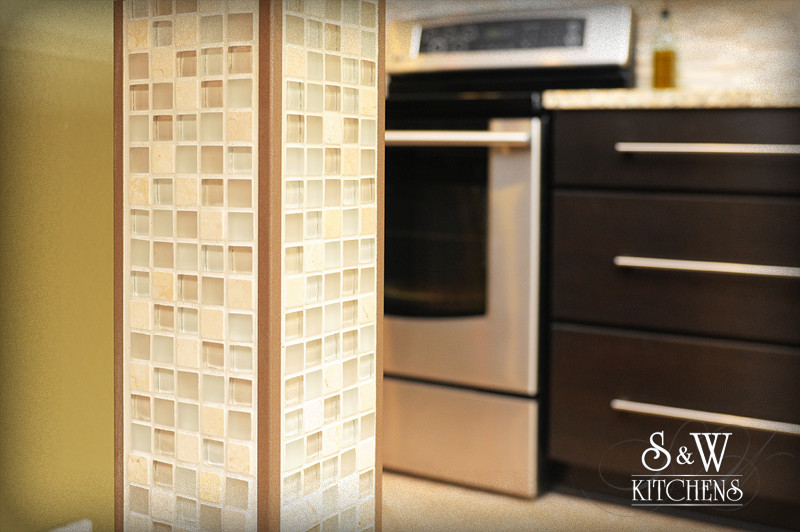 Kitchen - transitional galley kitchen idea in Orlando with a single-bowl sink, shaker cabinets, dark wood cabinets, granite countertops, beige backsplash, mosaic tile backsplash and stainless steel appliances