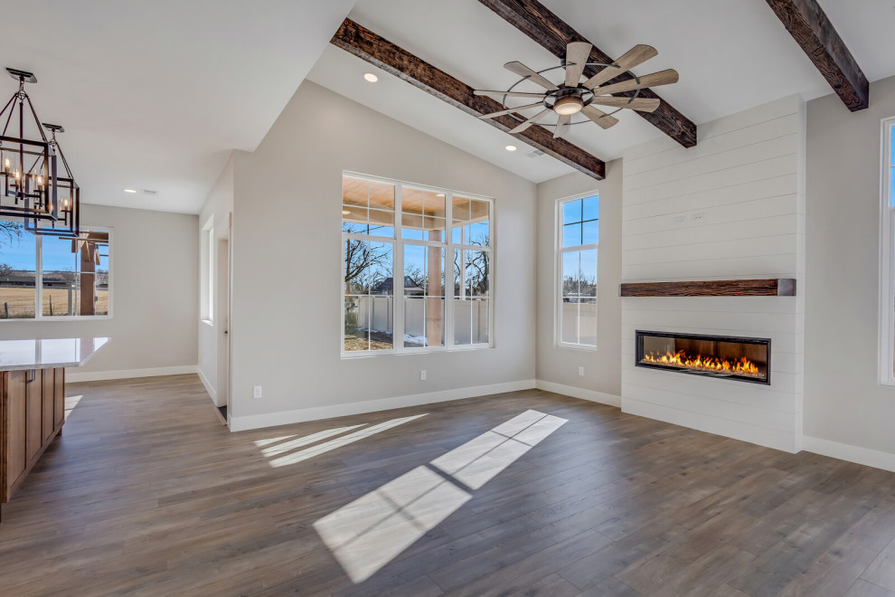 Photo of a mid-sized country open concept living room in Other with grey walls, dark hardwood floors, a ribbon fireplace, brown floor and vaulted.