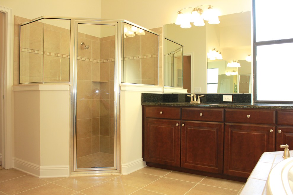 Large traditional bathroom in Tampa with an undermount sink, recessed-panel cabinets, dark wood cabinets, granite benchtops, a drop-in tub, a corner shower, beige tile, ceramic tile, beige walls and ceramic floors.