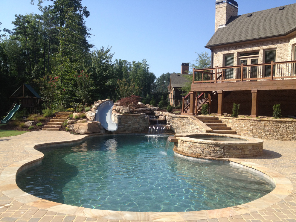 Large traditional backyard kidney-shaped lap pool in Atlanta with a water slide and brick pavers.