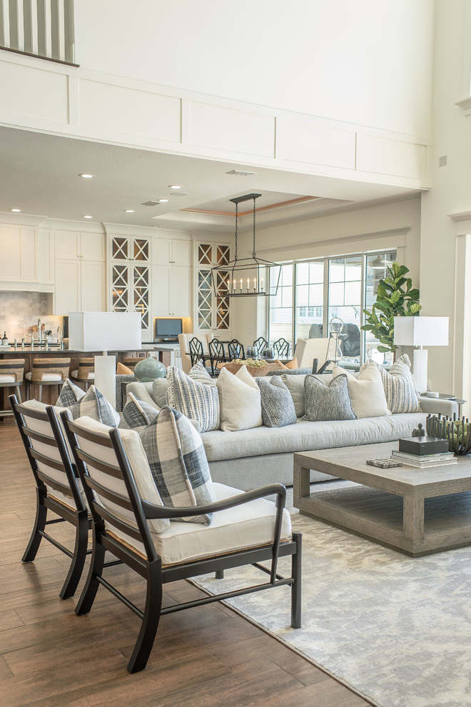 Family room - large coastal open concept medium tone wood floor and brown floor family room idea in Orlando with white walls, a standard fireplace, a wood fireplace surround and a media wall
