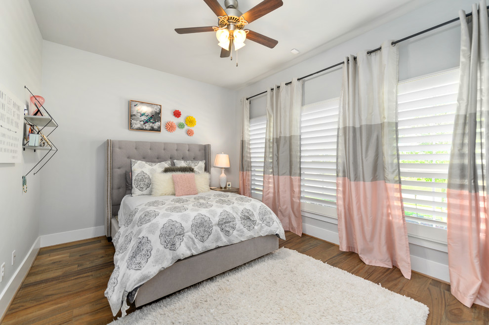 Photo of a mid-sized transitional guest bedroom in Houston with grey walls, medium hardwood floors and grey floor.