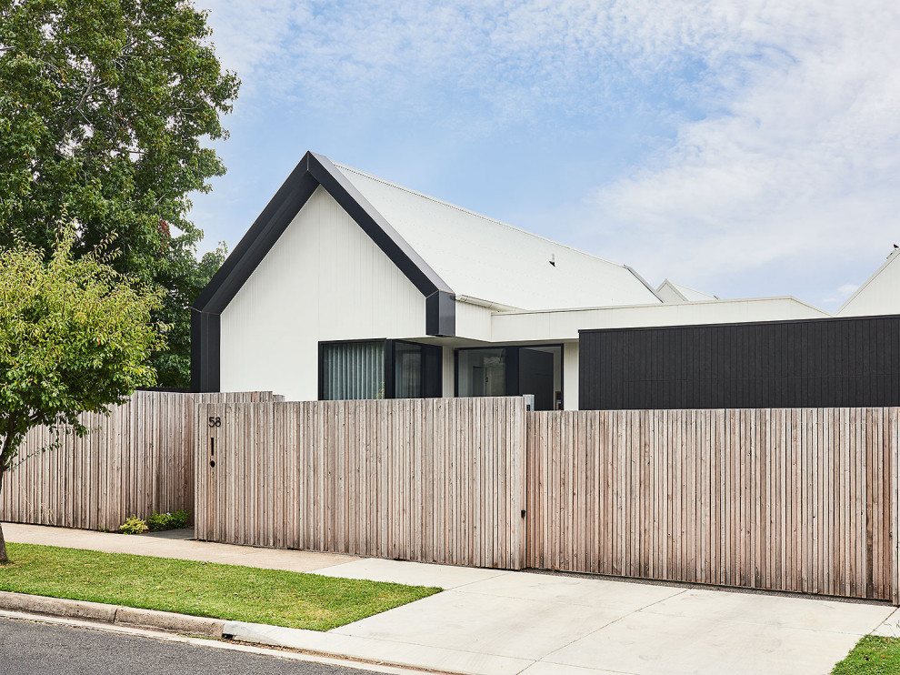 Large tropical one-storey white house exterior in Geelong with concrete fiberboard siding, a gable roof, a metal roof and a white roof.