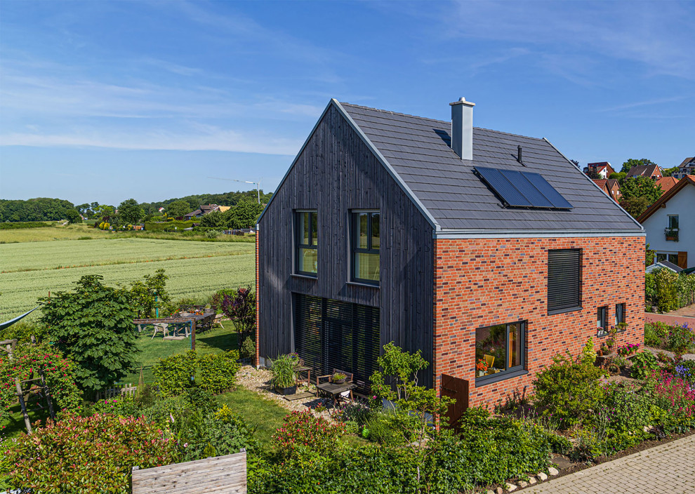 Modelo de fachada de casa gris y gris contemporánea de tamaño medio con revestimiento de madera, tejado a dos aguas, tejado de teja de barro y tablilla