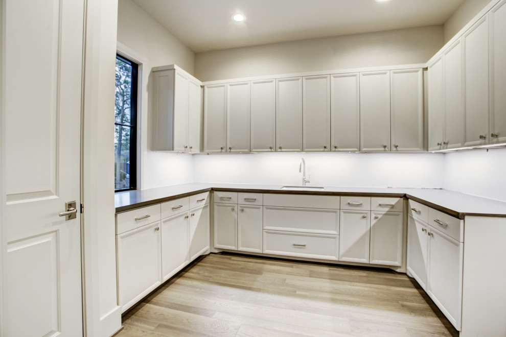 Geräumige Moderne Waschküche in U-Form mit Unterbauwaschbecken, Schrankfronten im Shaker-Stil, Quarzwerkstein-Arbeitsplatte, braunem Holzboden und braunem Boden in Houston