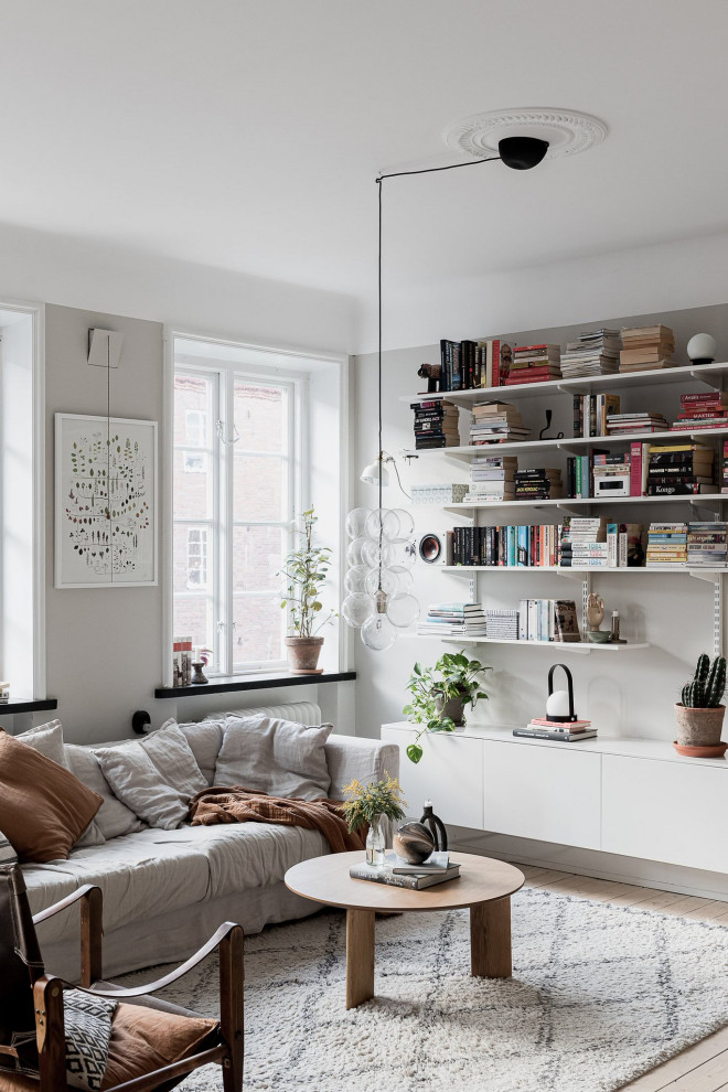 Inredning av ett minimalistiskt vardagsrum, med grå väggar, ljust trägolv och beiget golv