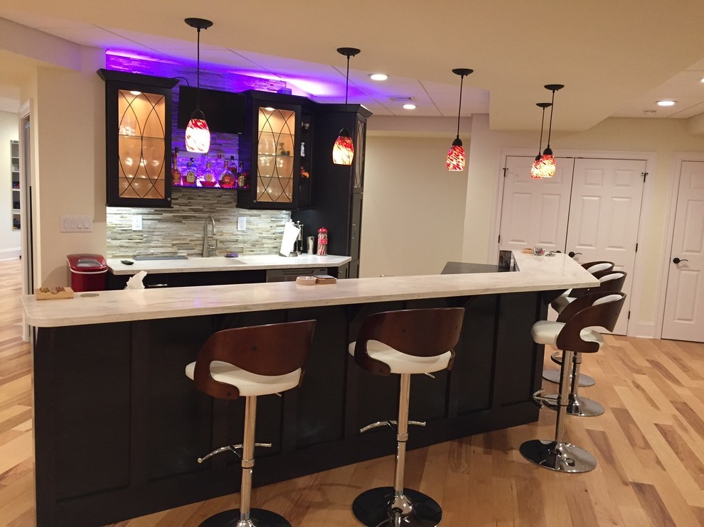 Inspiration for a large contemporary galley seated home bar in Philadelphia with an undermount sink, glass-front cabinets, dark wood cabinets, quartzite benchtops, grey splashback, matchstick tile splashback, light hardwood floors and beige floor.