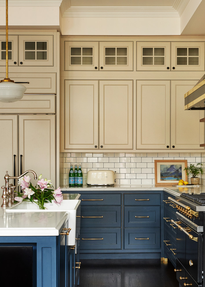 Large traditional l-shaped open plan kitchen in Toronto with a farmhouse sink, beaded inset cabinets, blue cabinets, quartz benchtops, white splashback, subway tile splashback, panelled appliances, with island, brown floor, white benchtop and dark hardwood floors.
