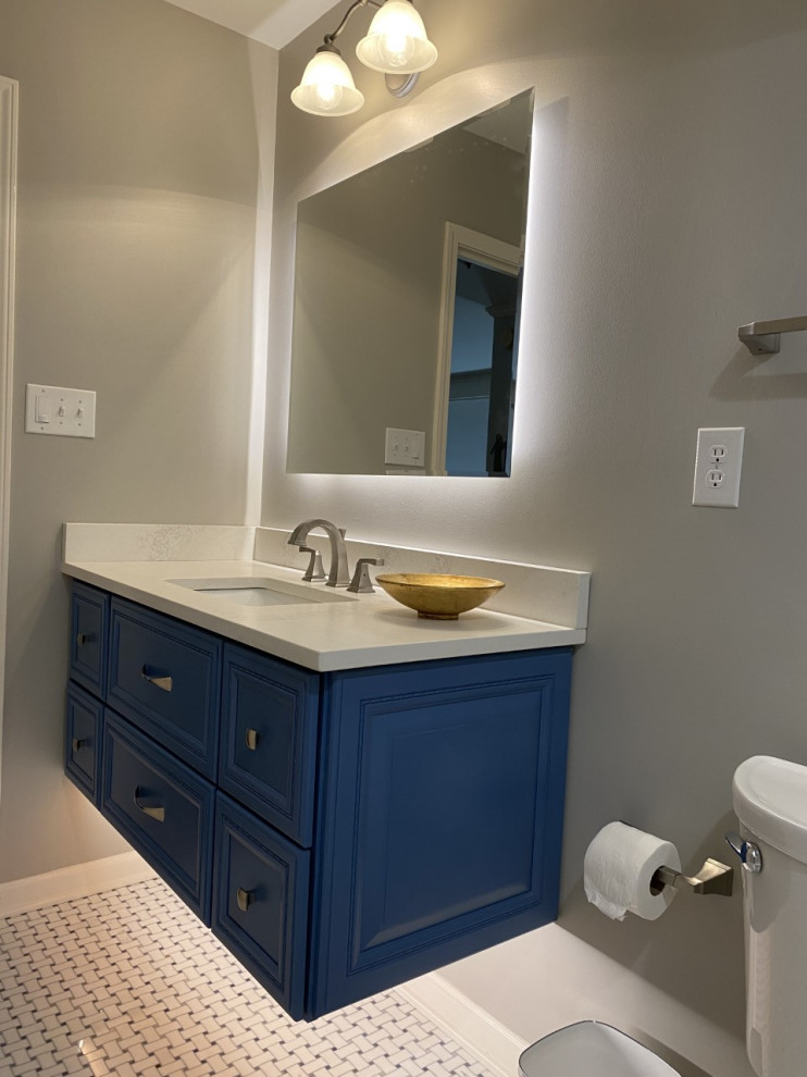 Klassisk inredning av ett litet vit vitt badrum för barn, med luckor med infälld panel, blå skåp, ett badkar i en alkov, en dusch i en alkov, en toalettstol med separat cisternkåpa, grå kakel, travertinkakel, marmorgolv, ett undermonterad handfat, bänkskiva i kvarts och blått golv