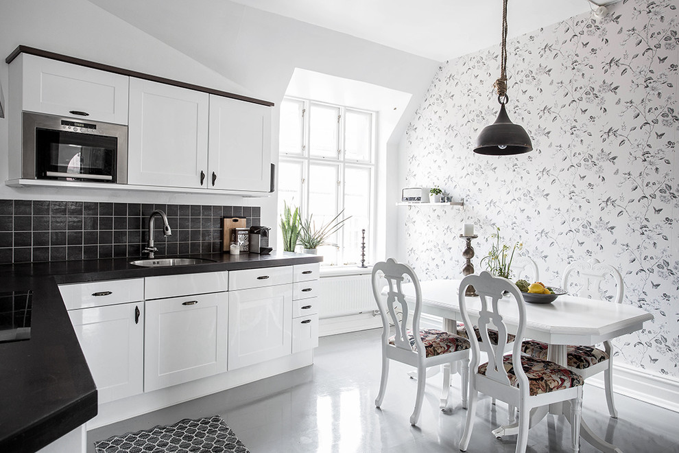 Design ideas for a mid-sized scandinavian l-shaped eat-in kitchen in Gothenburg with an undermount sink, shaker cabinets, white cabinets, black splashback, stainless steel appliances, concrete floors and no island.