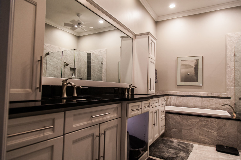 Drop-in bathtub - mid-sized transitional master gray tile and ceramic tile marble floor, gray floor and double-sink drop-in bathtub idea with shaker cabinets, white cabinets, a two-piece toilet, gray walls, an undermount sink, quartzite countertops, a hinged shower door, black countertops, a niche and a floating vanity