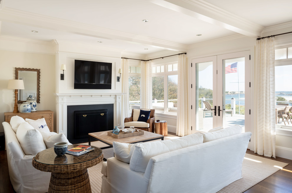 This is an example of a mid-sized beach style open concept living room in Providence with beige walls, dark hardwood floors, a standard fireplace, a wall-mounted tv and brown floor.