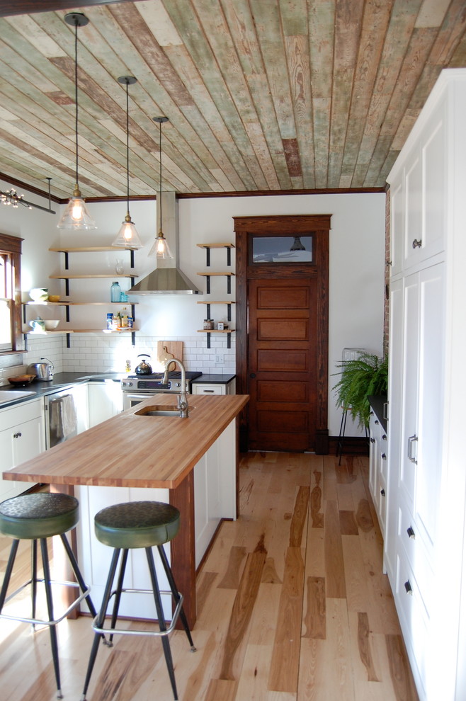 Inspiration for a mid-sized transitional l-shaped light wood floor enclosed kitchen remodel with an undermount sink, shaker cabinets, white cabinets, soapstone countertops, white backsplash, subway tile backsplash and an island