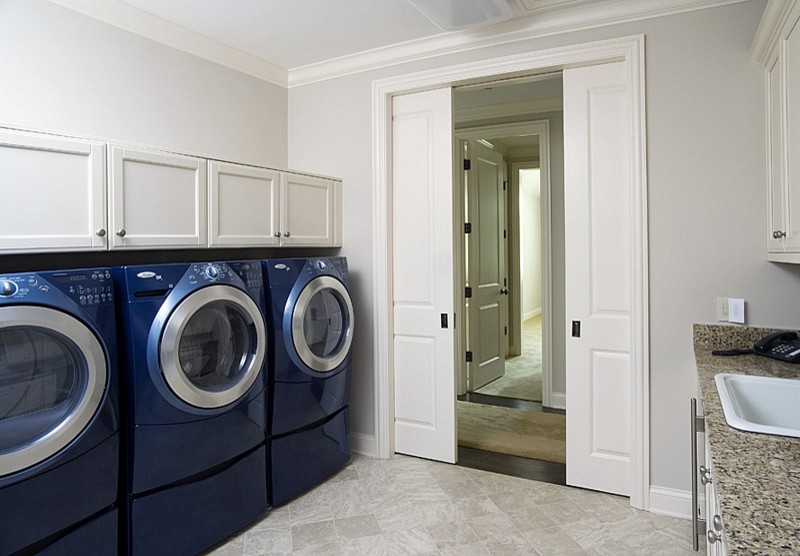 Design ideas for an expansive traditional galley dedicated laundry room in Chicago with a drop-in sink, recessed-panel cabinets, white cabinets, granite benchtops, limestone floors, a side-by-side washer and dryer and grey walls.