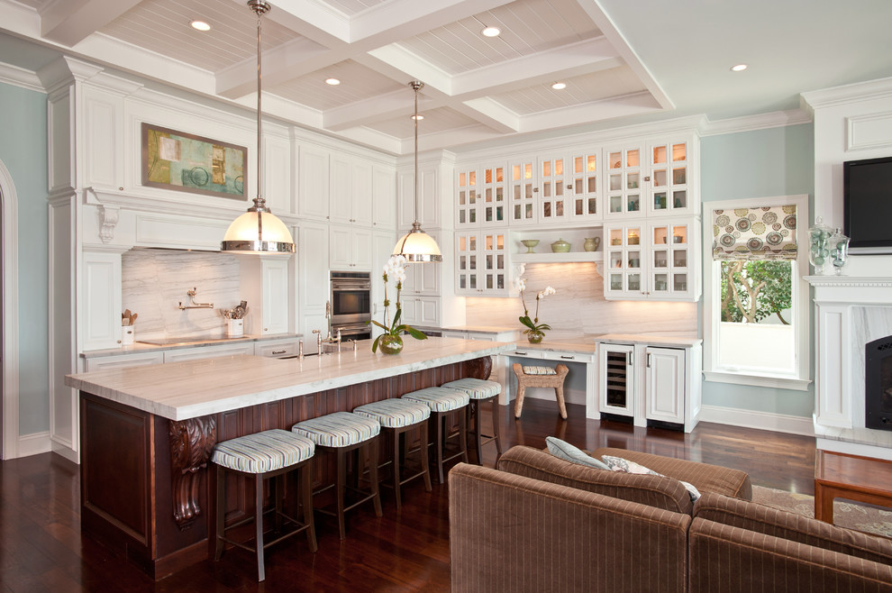 This is an example of a traditional l-shaped open plan kitchen in Tampa with glass-front cabinets, white cabinets and white splashback.