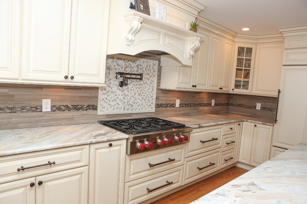 Inspiration for a large transitional u-shaped light wood floor eat-in kitchen remodel in Newark with an undermount sink, raised-panel cabinets, distressed cabinets, granite countertops, brown backsplash, mosaic tile backsplash, stainless steel appliances and an island