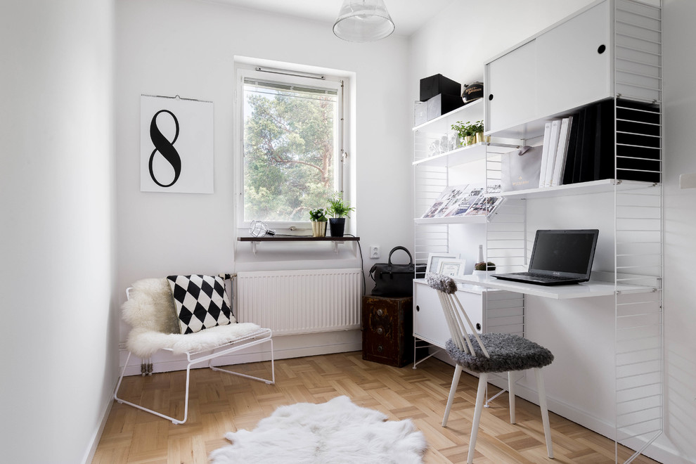 Mid-sized scandinavian study room in Stockholm with white walls, medium hardwood floors, a built-in desk and no fireplace.