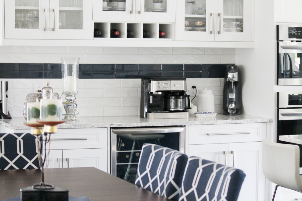 Example of a large transitional u-shaped eat-in kitchen design with shaker cabinets, white cabinets, quartz countertops, white backsplash, subway tile backsplash, stainless steel appliances, an island and gray countertops
