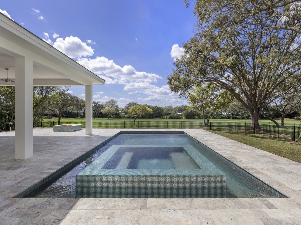 This is an example of a mid-sized transitional backyard rectangular pool in Orlando with a hot tub and natural stone pavers.
