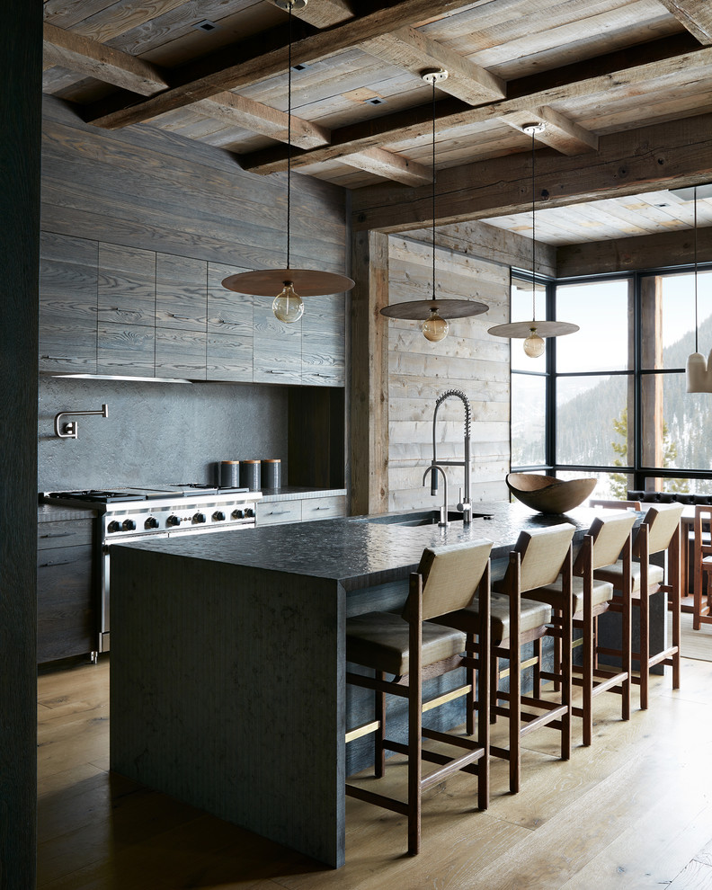 Inspiration for a country galley eat-in kitchen in Other with an undermount sink, flat-panel cabinets, dark wood cabinets, grey splashback, stainless steel appliances, light hardwood floors, with island, beige floor and black benchtop.
