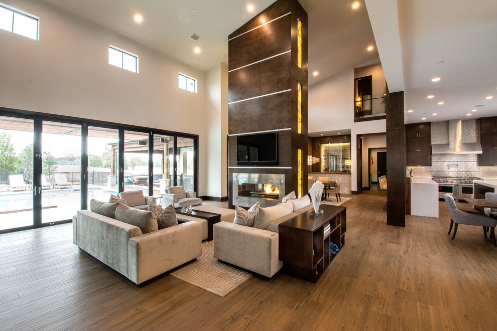 Inspiration for an expansive contemporary open concept living room in Orange County with grey walls, a two-sided fireplace, a metal fireplace surround, porcelain floors and brown floor.