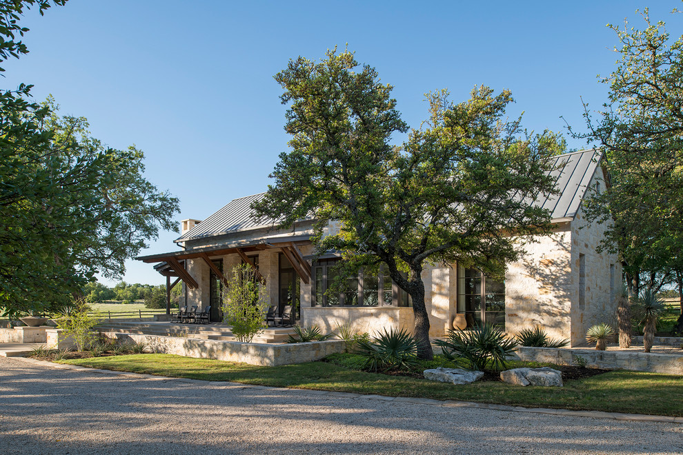 Mid-sized contemporary one-storey beige house exterior in Austin with stone veneer and a metal roof.