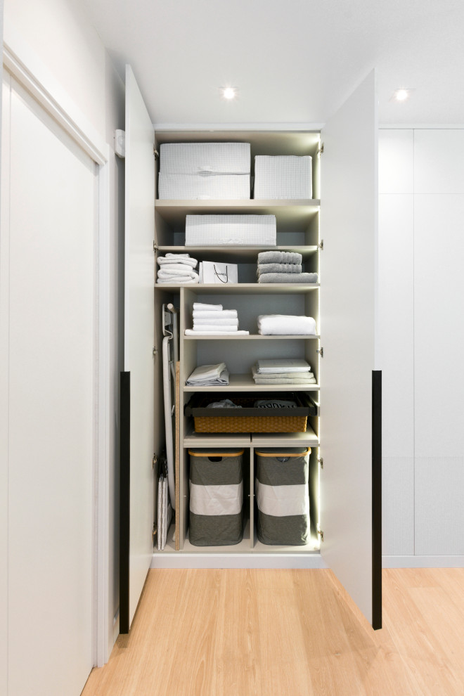 Large contemporary gender-neutral walk-in wardrobe in Other with raised-panel cabinets, white cabinets, laminate floors and brown floor.