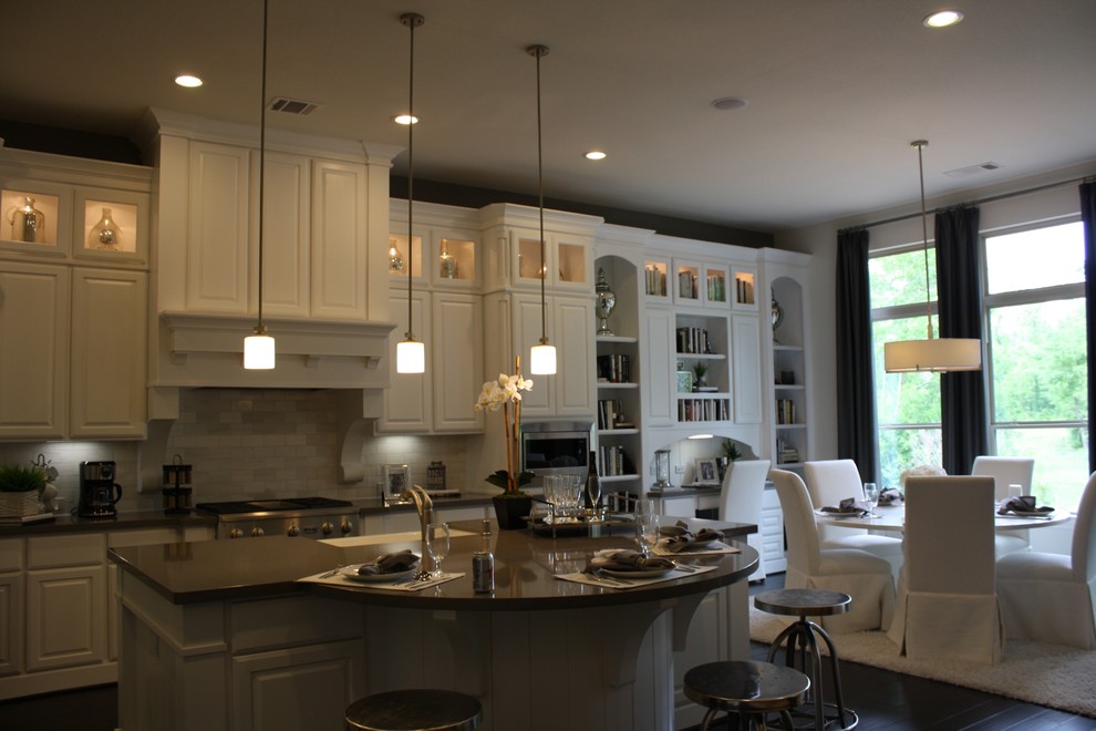 Eat-in kitchen - mid-sized transitional dark wood floor and brown floor eat-in kitchen idea in Houston with a farmhouse sink, raised-panel cabinets, white cabinets, solid surface countertops, beige backsplash, stone tile backsplash and an island