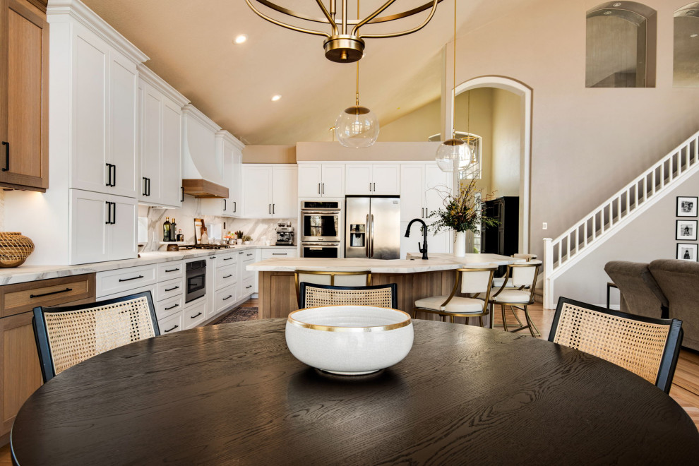 Design ideas for a large country l-shaped open plan kitchen in Denver with a farmhouse sink, recessed-panel cabinets, light wood cabinets, quartz benchtops, white splashback, engineered quartz splashback, stainless steel appliances, light hardwood floors, with island, beige floor and white benchtop.