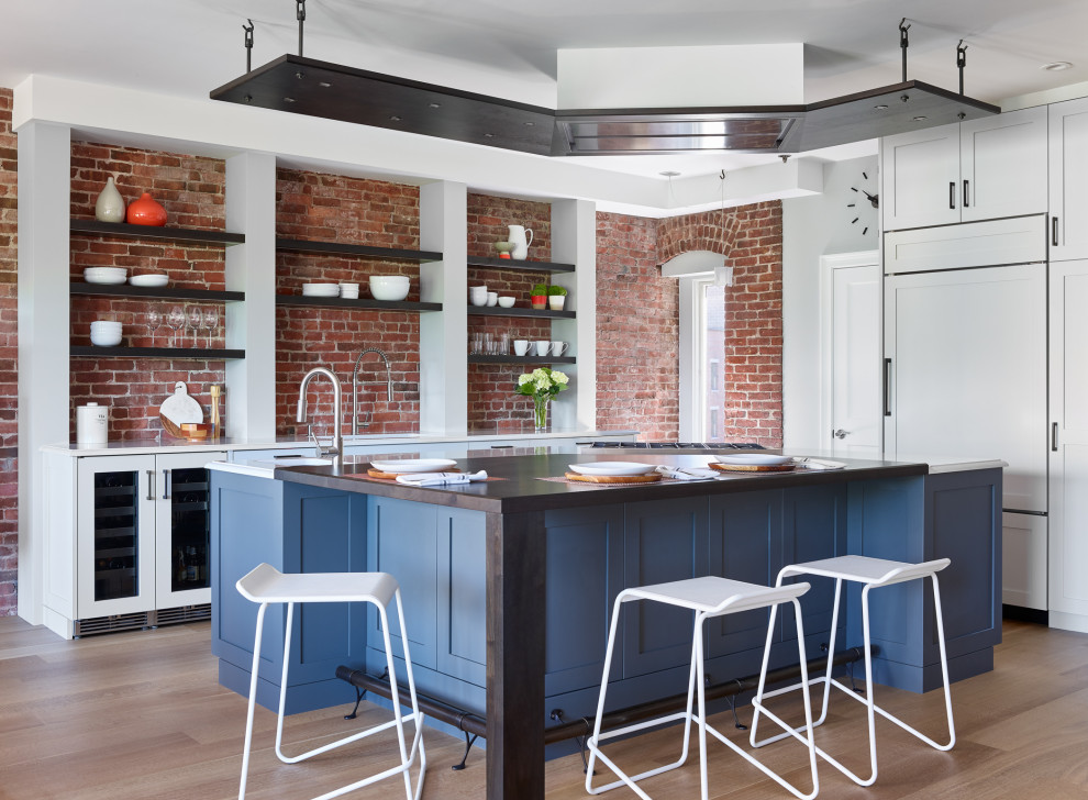 Inspiration for a transitional u-shaped medium tone wood floor and brown floor open concept kitchen remodel in Boston with an undermount sink, shaker cabinets, white cabinets, quartz countertops, red backsplash, brick backsplash, paneled appliances, an island and white countertops
