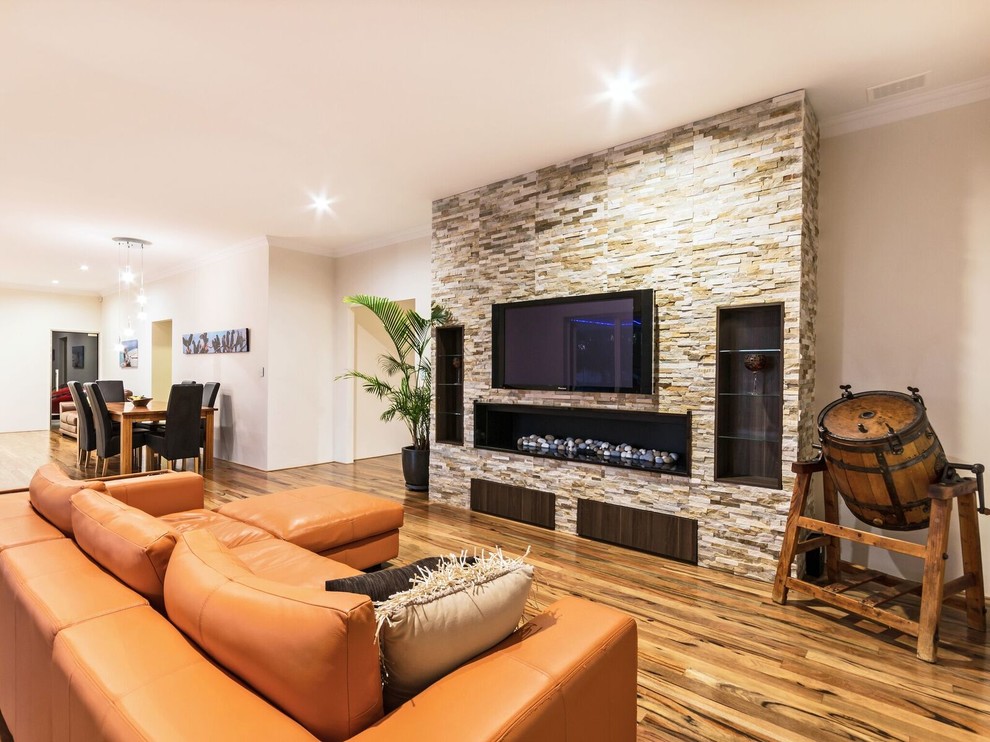 Photo of a country open concept living room in Perth with beige walls, dark hardwood floors, a standard fireplace, a stone fireplace surround and a wall-mounted tv.