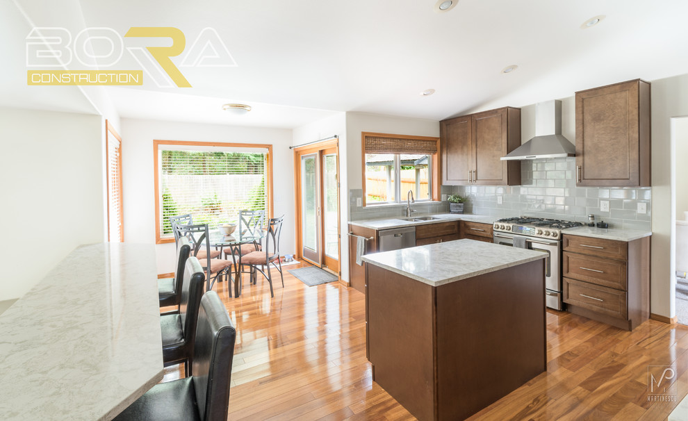 Eat-in kitchen - mid-sized transitional l-shaped medium tone wood floor and brown floor eat-in kitchen idea with an undermount sink, shaker cabinets, medium tone wood cabinets, quartz countertops, gray backsplash, ceramic backsplash, stainless steel appliances and an island