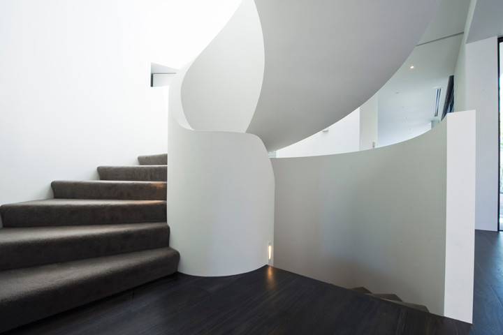 This is an example of a large modern carpeted spiral staircase in Melbourne with carpet risers.