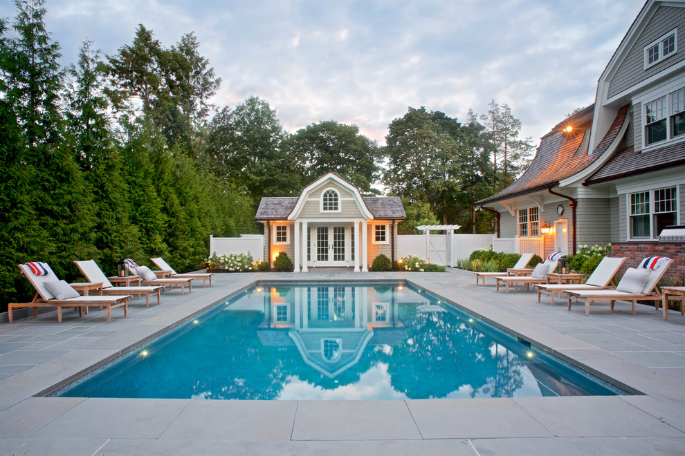 Inspiration for a large traditional backyard rectangular lap pool in New York with a pool house and natural stone pavers.