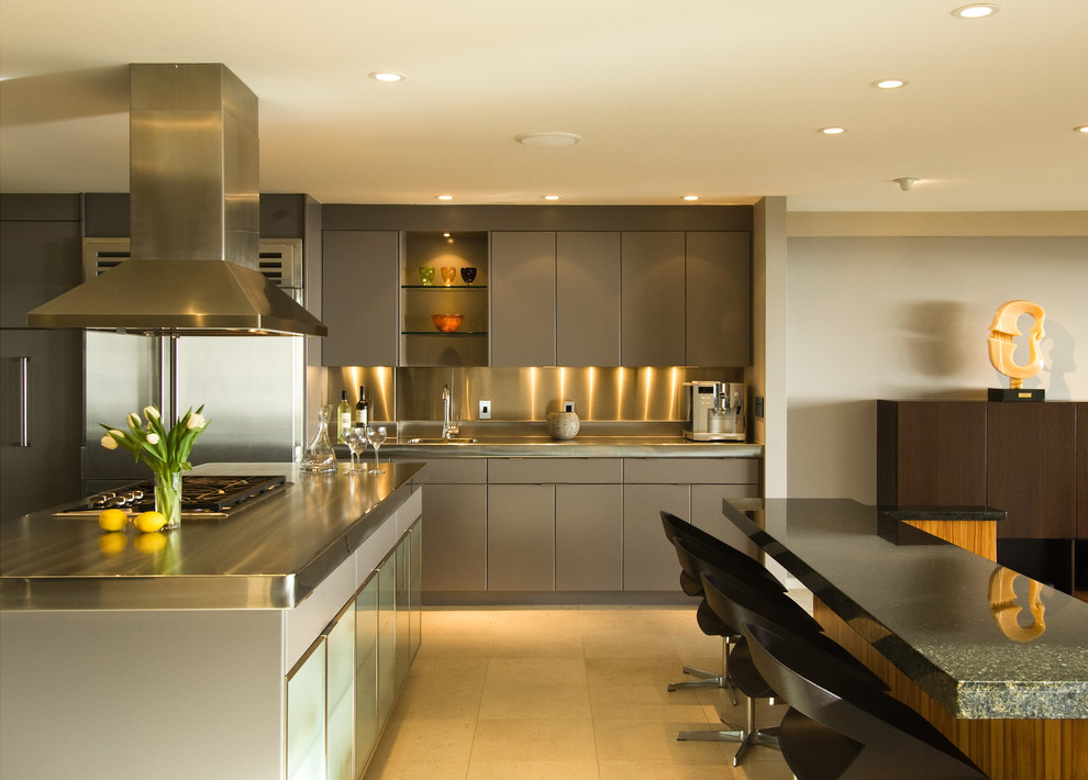 Photo of a large contemporary u-shaped open plan kitchen in Hawaii with an integrated sink, flat-panel cabinets, grey cabinets, stainless steel benchtops, metallic splashback, metal splashback, stainless steel appliances, ceramic floors, with island, beige floor and multi-coloured benchtop.