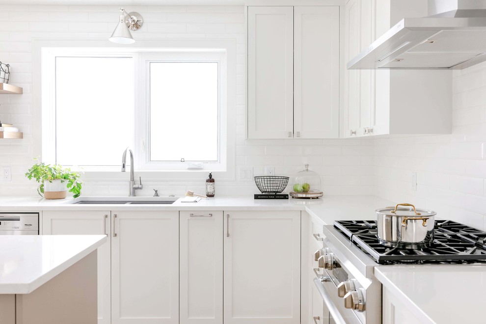 Eat-in kitchen - large transitional u-shaped medium tone wood floor and brown floor eat-in kitchen idea in Calgary with an undermount sink, shaker cabinets, white cabinets, quartzite countertops, white backsplash, subway tile backsplash, stainless steel appliances, an island and white countertops